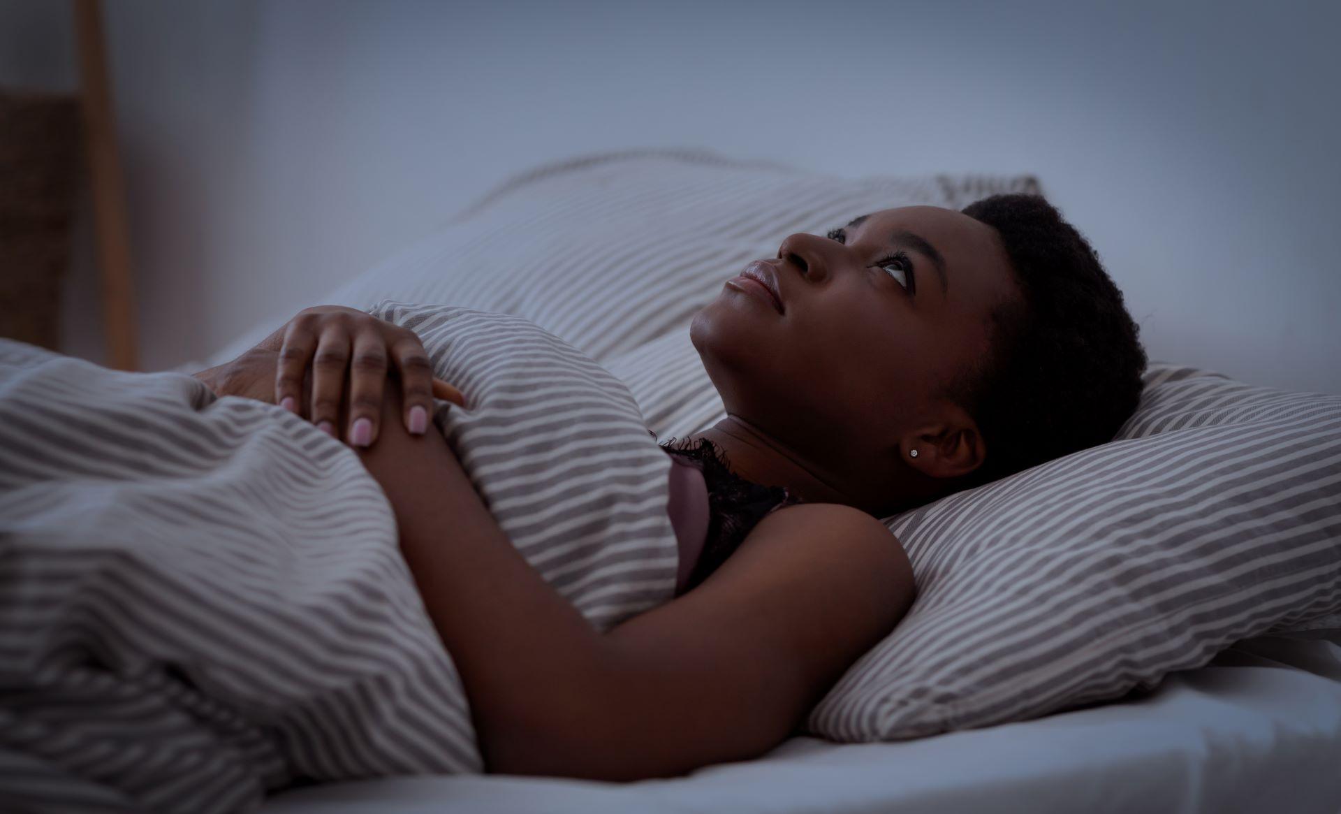Frau liegt wach im Bett mit Schlafproblemen