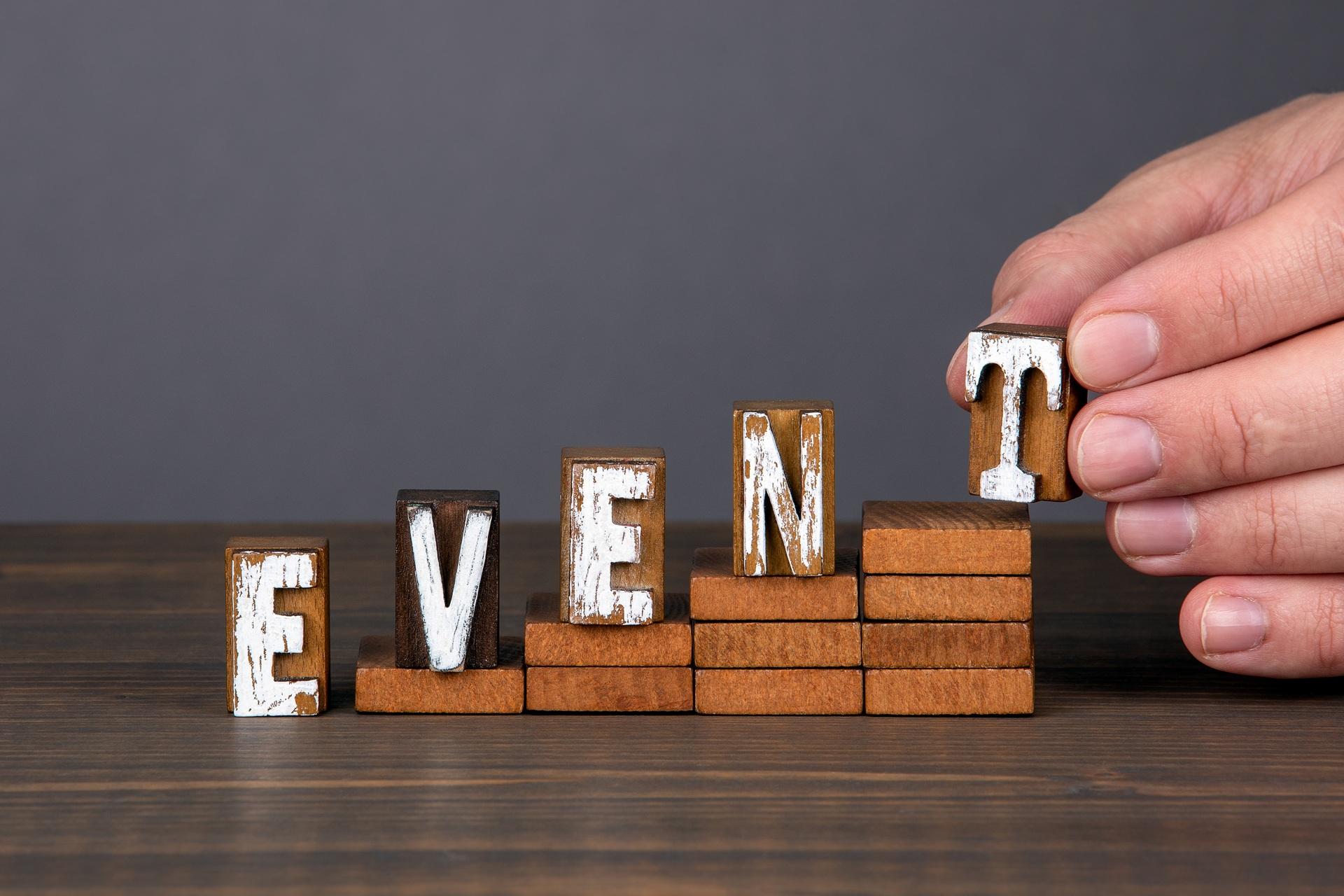 Hand bildet das Wort Event aus Holzklötzen | Event Zelt